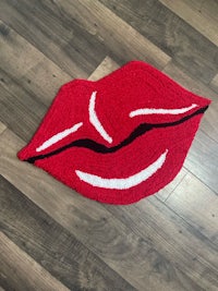 a red lip shaped rug on a wooden floor