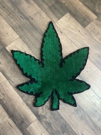 a green marijuana leaf rug on a wooden floor