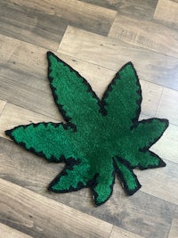 a green marijuana leaf rug on a wooden floor