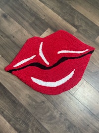 a red and white lip rug on a wooden floor