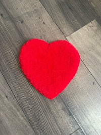 a red heart shaped rug on a wooden floor