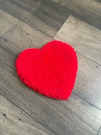 a red heart shaped rug on a wooden floor